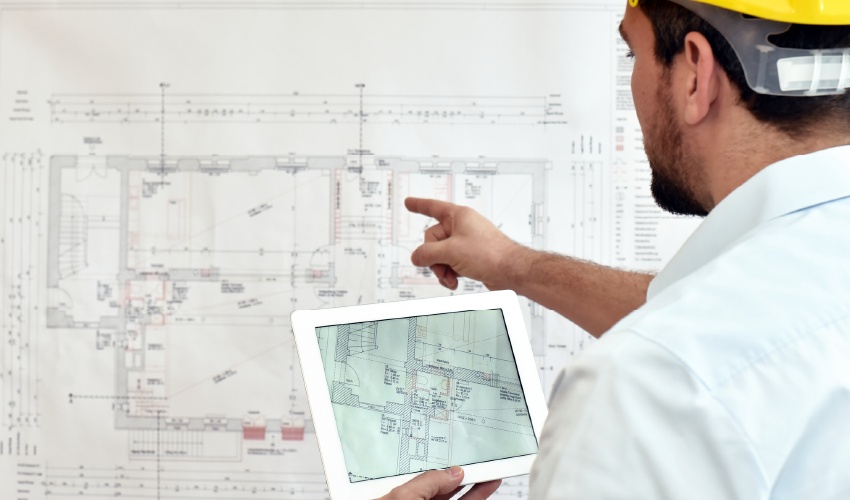 Una persona señalando una pizarra llena de bocetos y líneas. Aplicando lo aprendido de la carrera de Ingeniería en Geomensura. Foto extraída de iStock bajo la licencia estándar.
