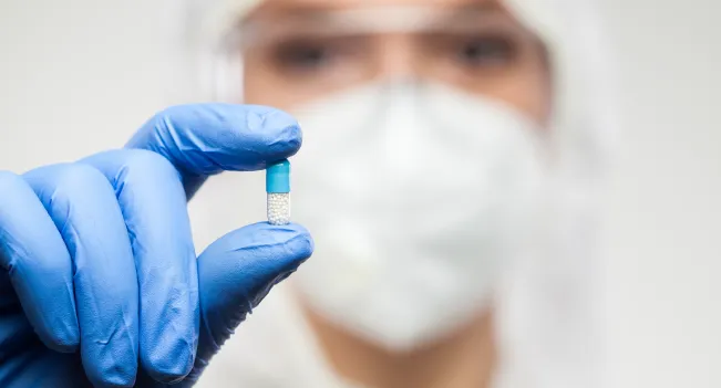 Auxiliar de farmacia enseñando una pildora